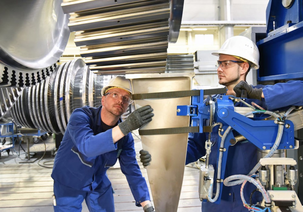 Teamwork - workers manufacturing steam turbines in an industrial factory