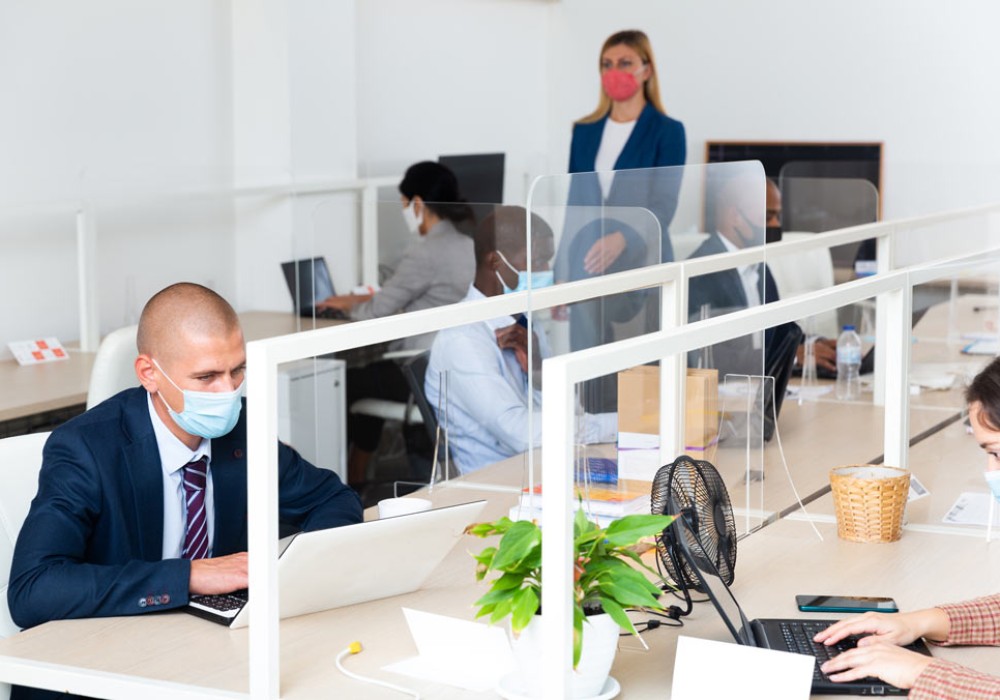 Focused businessman in disposable face mask working on laptop in office. Necessary precautions during COVID 19 pandemic..