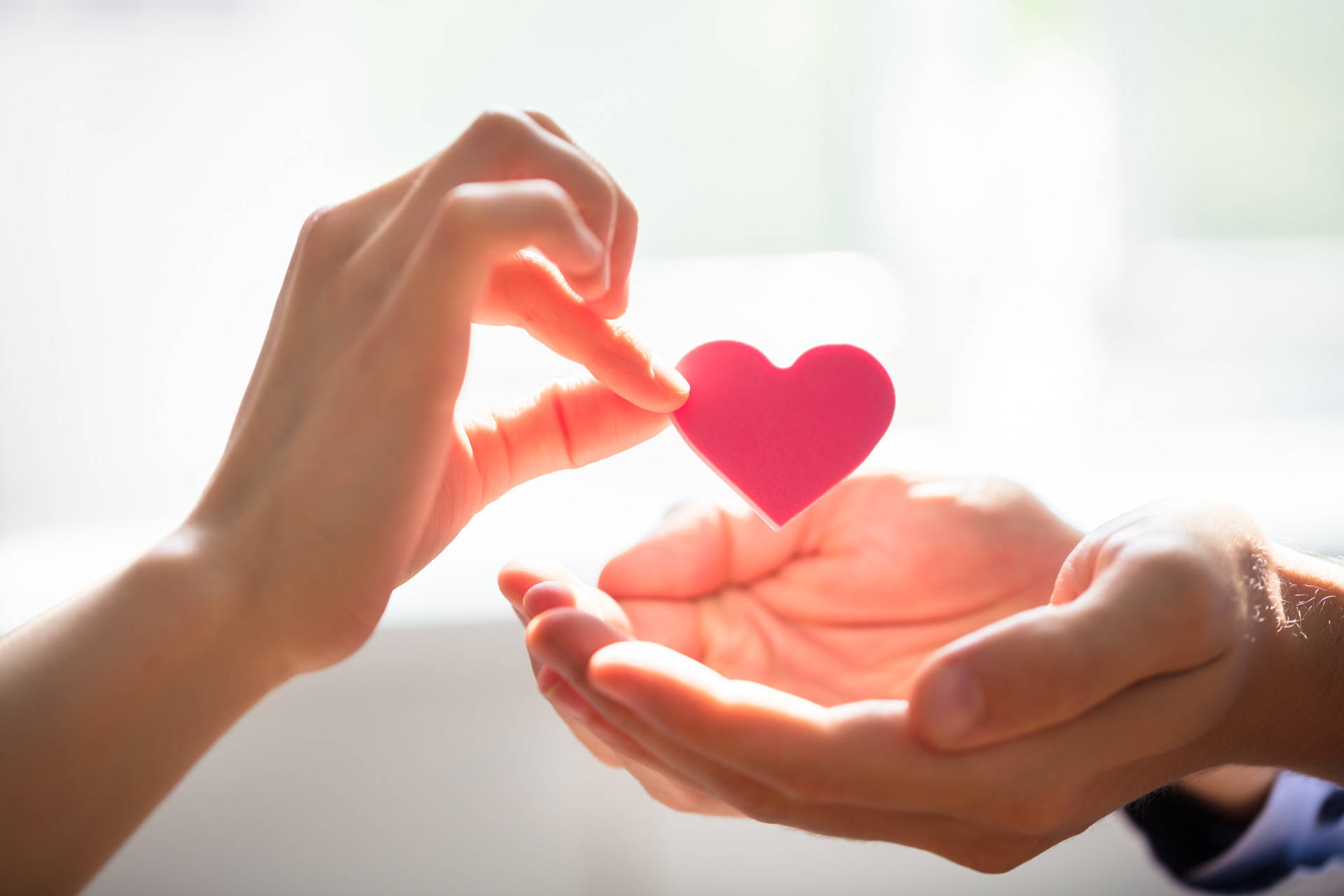 Close-up Of Woman Giving Red Heart On Man's Hand